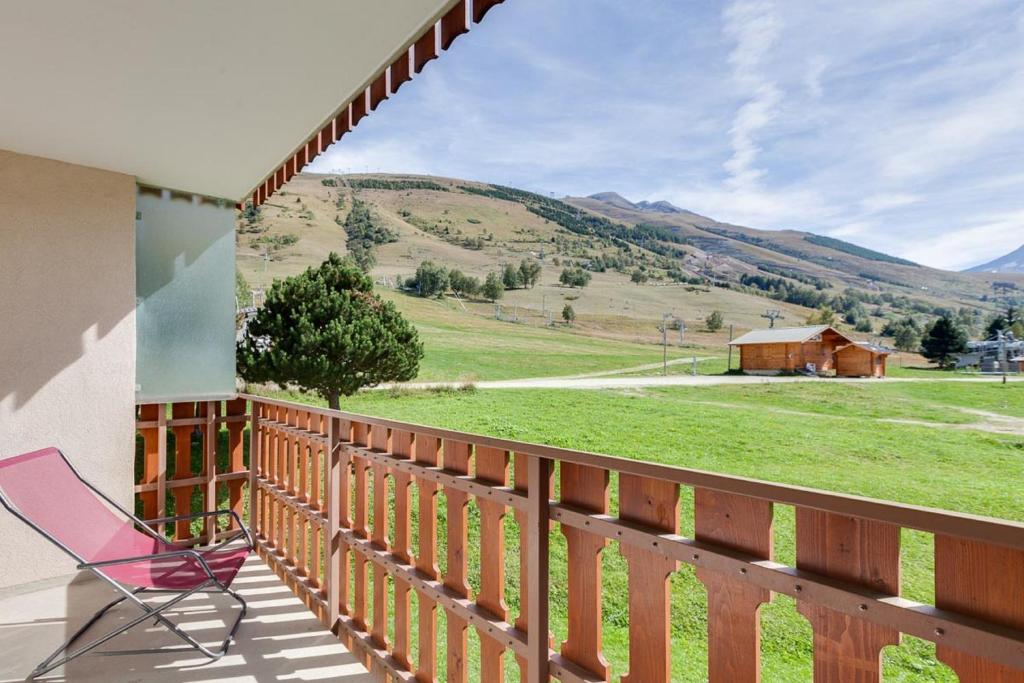 une chaise rose sur un balcon avec vue sur un champ dans l'établissement Vacancéole - Résidence Champamé, à Les Deux Alpes