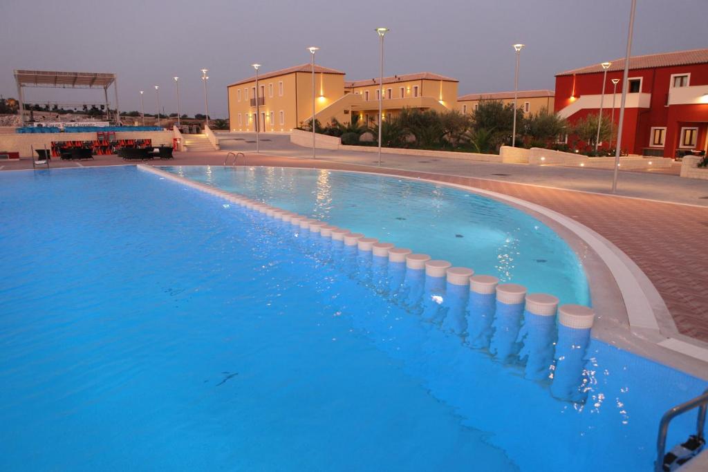 una gran piscina de agua azul por la noche en Hotel Borgo Don Chisciotte en Modica