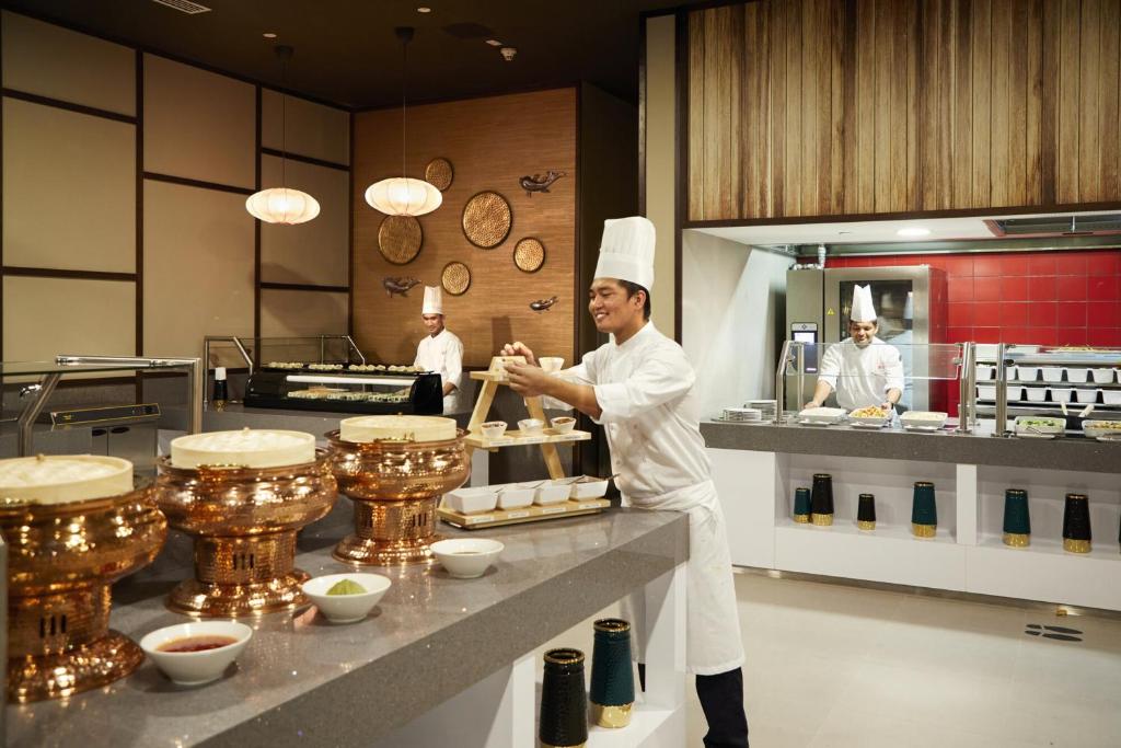 a chef standing in a kitchen preparing food at Riu Dubai Beach Resort - All Inclusive in Dubai