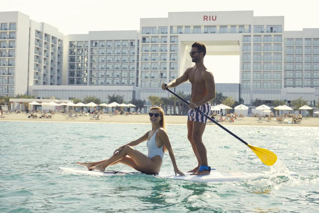 a man and a woman on a surfboard in the water at Riu Dubai Beach Resort - All Inclusive in Dubai