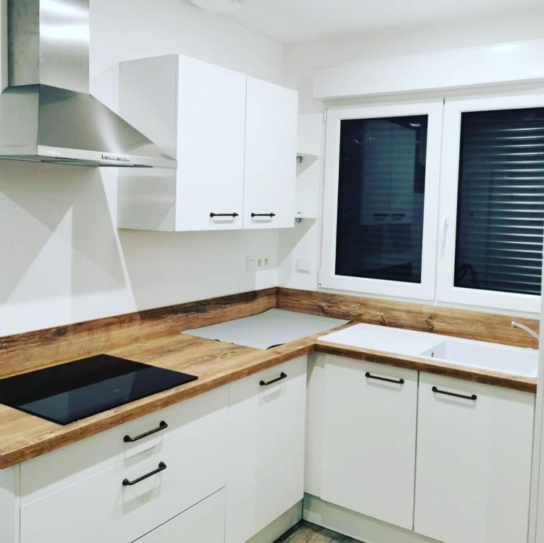 a white kitchen with white cabinets and windows at Les Cottages Barisiens in Bar-le-Duc