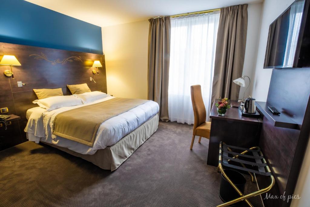 a hotel room with a large bed and a television at Élysée Hôtel in Châteauroux