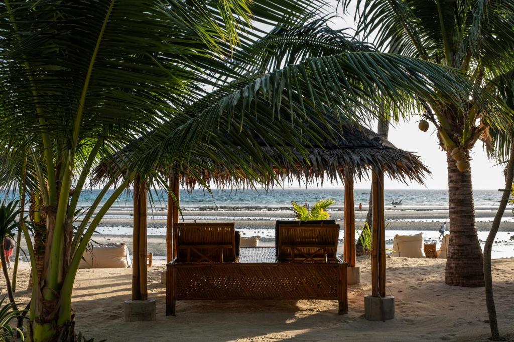 een tafel en stoelen onder palmbomen op het strand bij Amihan Beach Cabanas in Bantayan