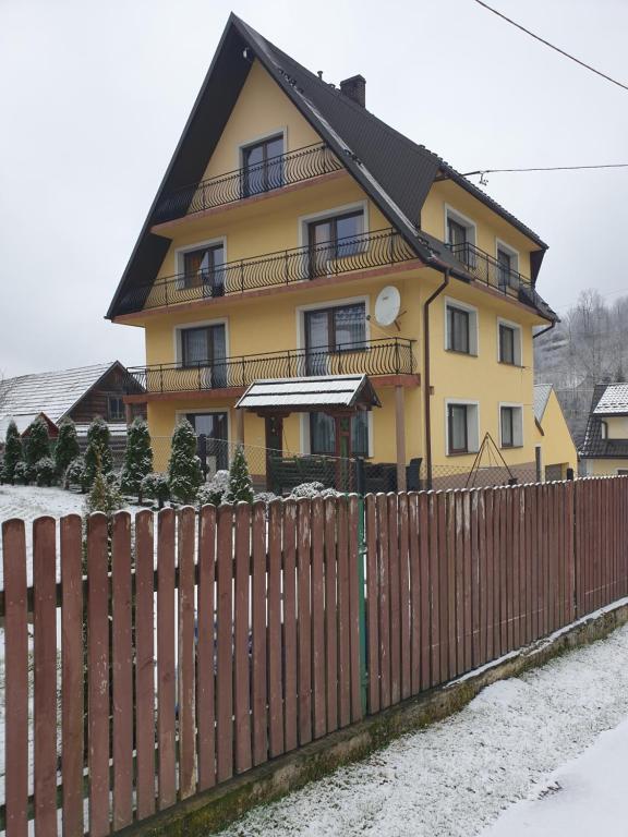 una casa gialla con una recinzione di fronte di Noclegi w gorcach a Ponice