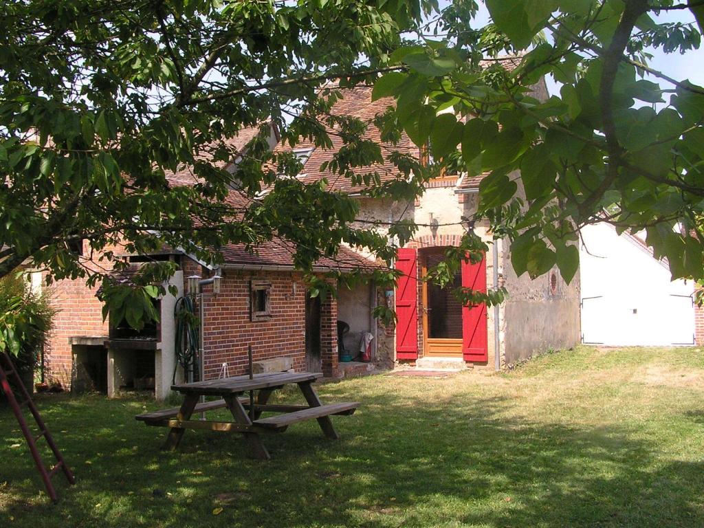 a picnic table in front of a brick house with a red door at Gîte de Lavau in Lavau