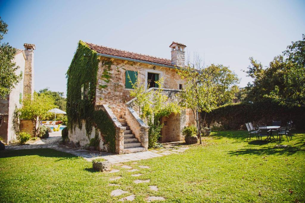 una antigua casa de piedra con un patio de césped en Arbalovija Rustic Villa, en Šivati