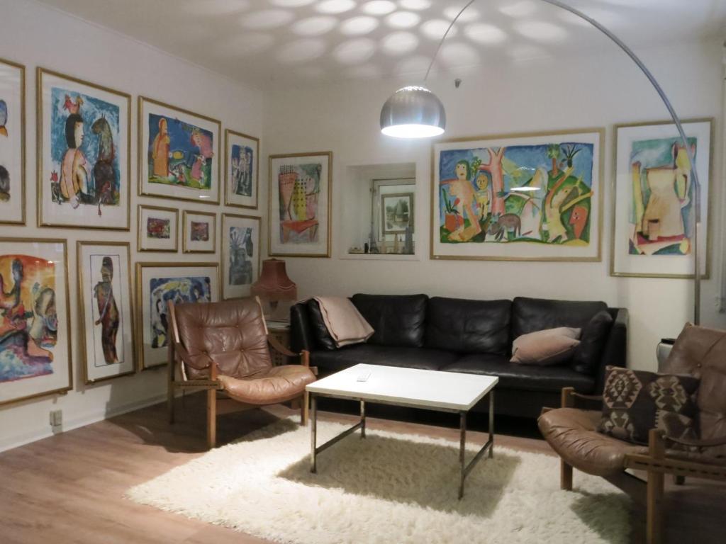 un soggiorno con divano nero e alcuni dipinti di ApartmentInCopenhagen Apartment 1316 a Copenaghen