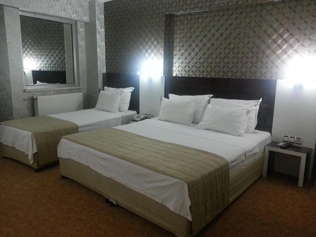 a hotel room with two beds and a mirror at Anya Suit Otel in Denizli