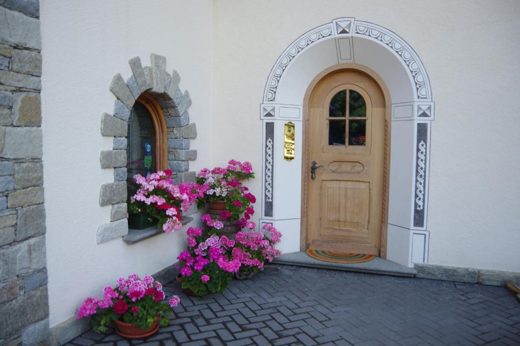 une porte et des fleurs sur le côté du bâtiment dans l'établissement Casa Caste, à Bormio