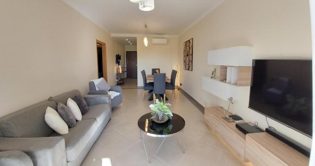 een woonkamer met een bank en een flatscreen-tv bij Paz em Resort de Luxo. in Cabanas de Tavira