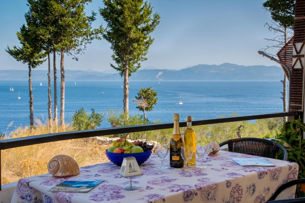 una mesa con botellas de vino y un bol de fruta en Casa Soula, Gaios Seaview Cottage, en Gáios
