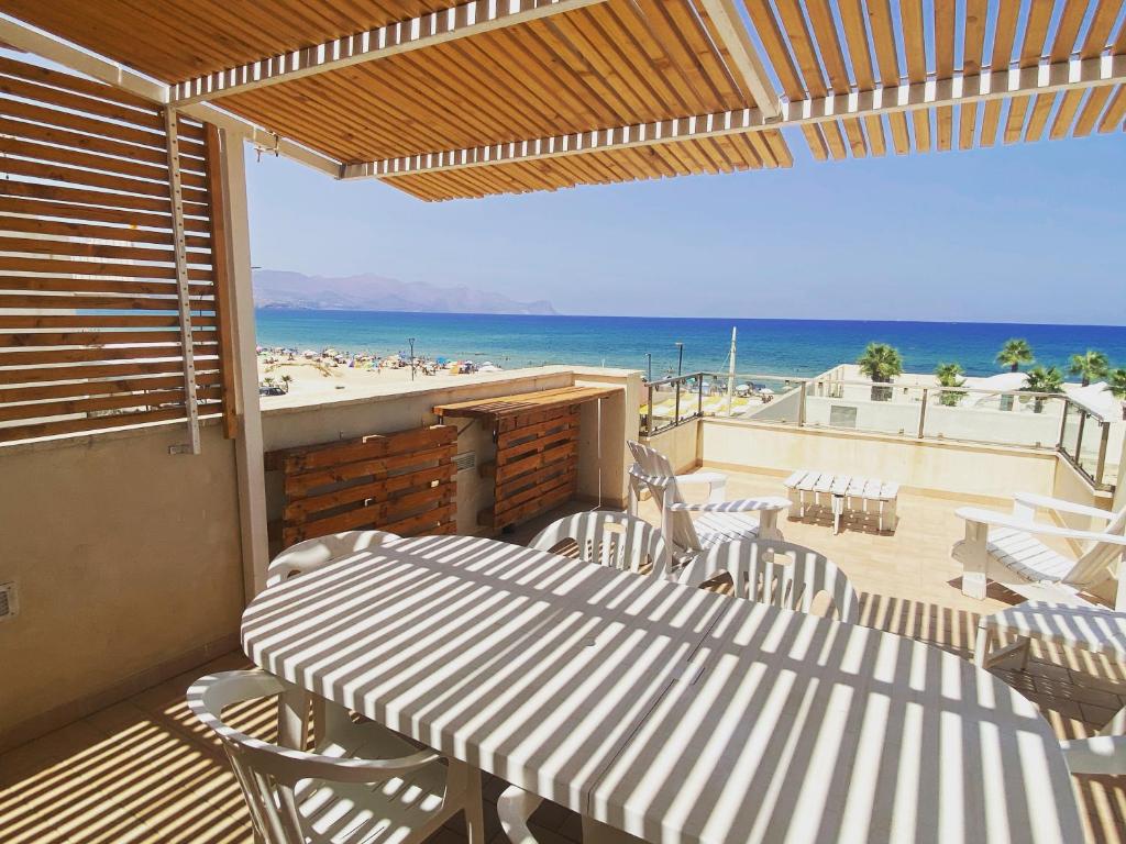 um pátio com uma mesa e cadeiras e a praia em Tonnara Apartments em Alcamo Marina