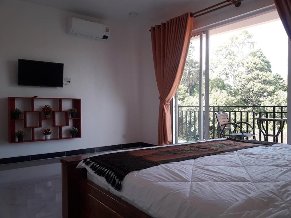 a bedroom with a bed and a balcony with a window at Khun Pich Apartments in Siem Reap