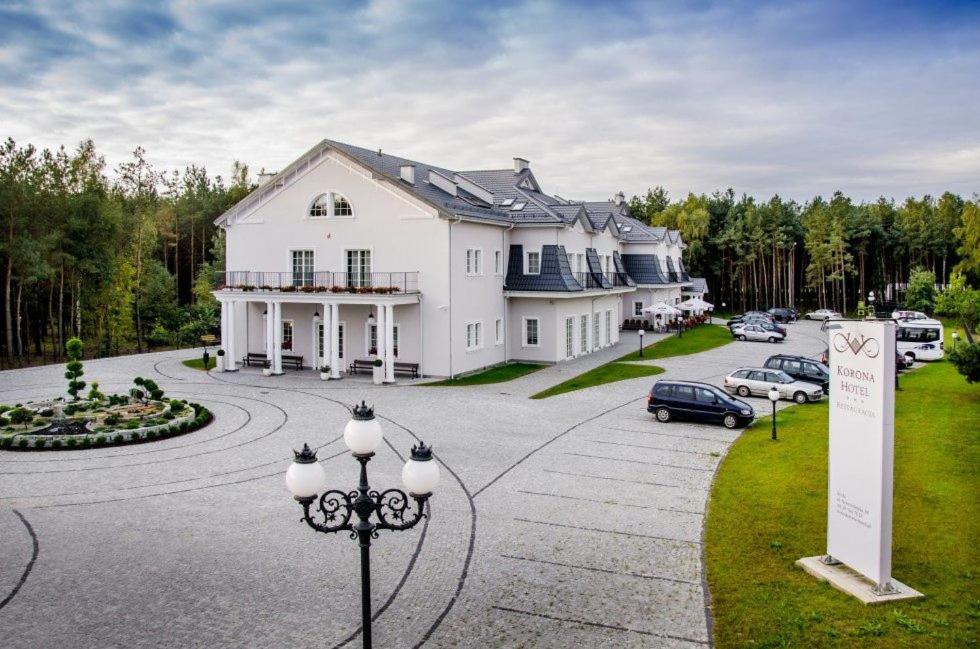 a large white house with cars parked in a driveway at Korona Hotel in Ostrołęka