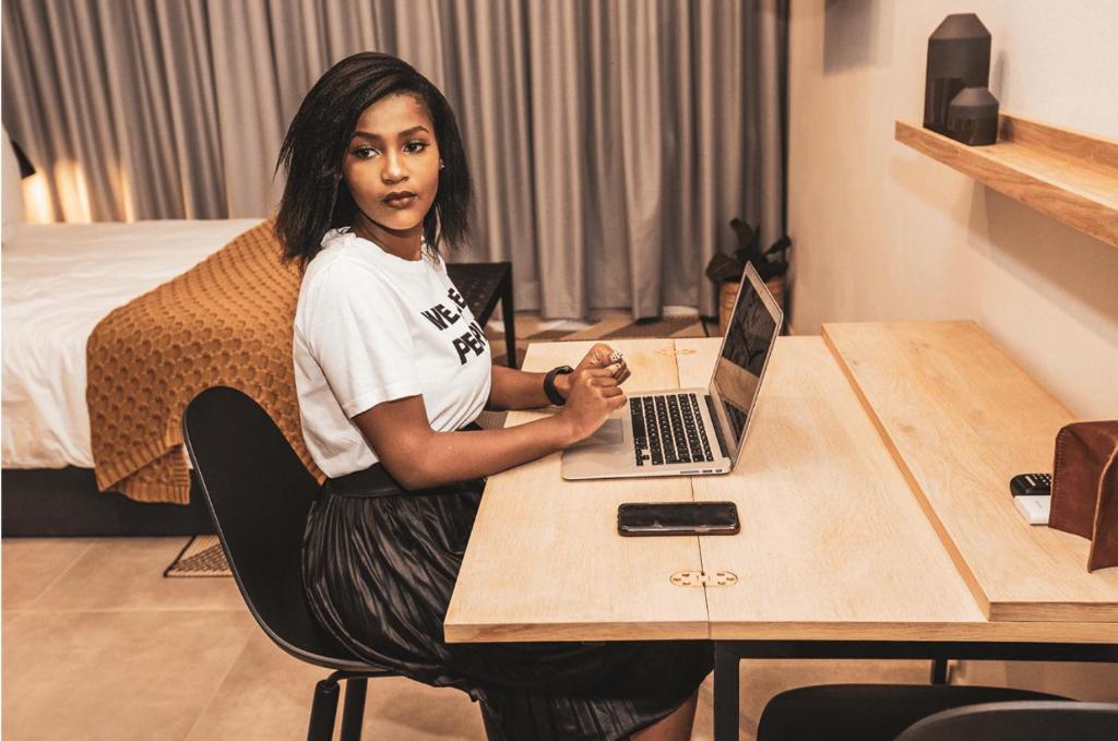 uma mulher sentada numa mesa com um laptop em Blackbrick Sandton One em Joanesburgo