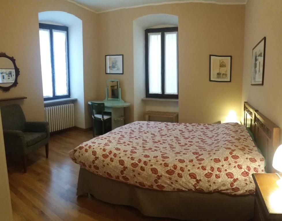 a bedroom with a bed and a chair and windows at Palazzo Fregoso in Garda