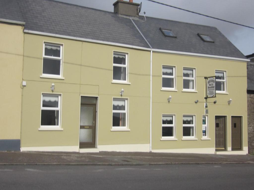 un edificio amarillo y verde al lado de una calle en Devanes B&B, en Dingle