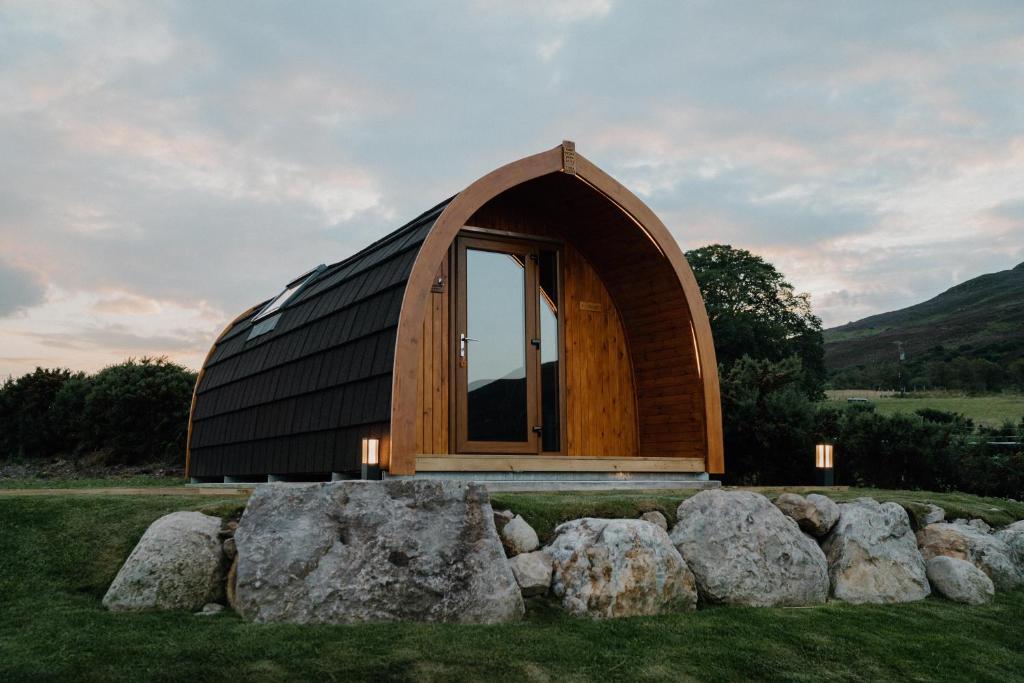 a wooden dome house with rocks in a field at North Coast 500 Pods - Brora in Brora