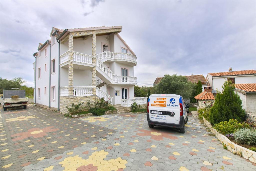 une camionnette blanche garée devant un bâtiment dans l'établissement Apartments Ljubica, à Murter