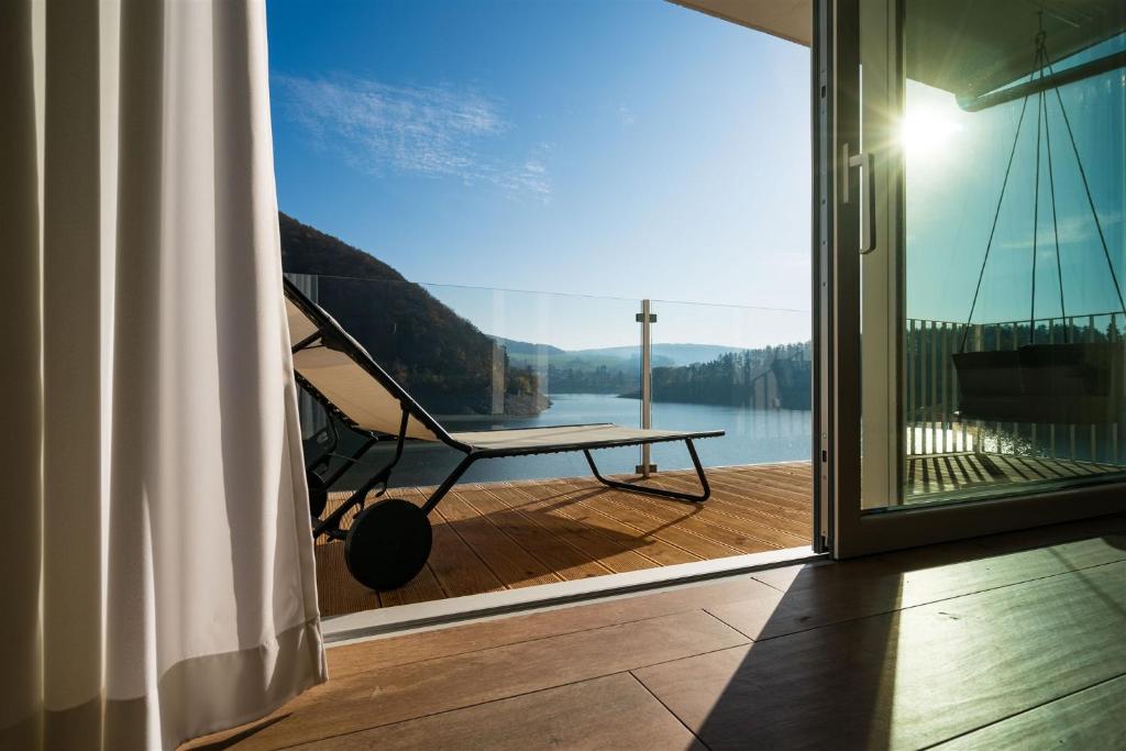 a porch with a swing and a view of a lake at 10 am See - auf der Sonnenseite in Diemelsee
