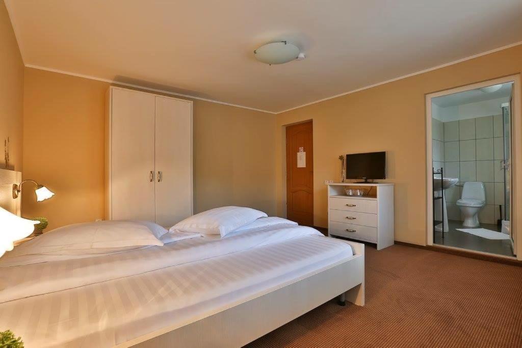 - une chambre avec un grand lit blanc et une salle de bains dans l'établissement Pensiunea La Padure Cheia, Prahova, à Măneciu