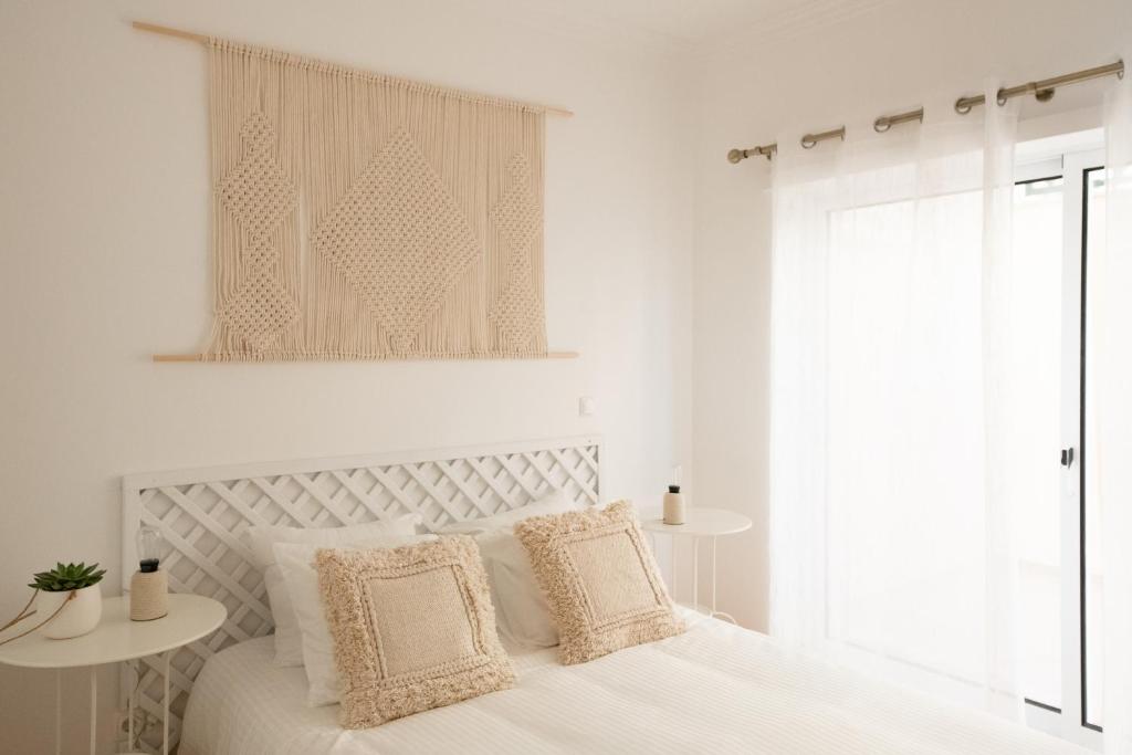 a white bedroom with a white bed with pillows at Casa do Ar in Sesimbra