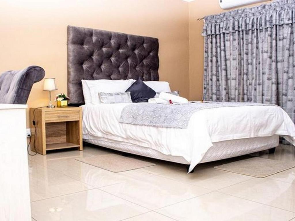 ein Schlafzimmer mit einem großen Bett mit einem großen Kopfteil in der Unterkunft Belz Boutique Hotel in Ixopo