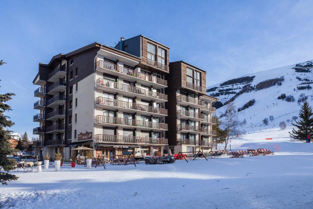 un grand bâtiment dans la neige devant une montagne dans l'établissement Vacancéole - Résidence Lauvitel, à Les Deux Alpes