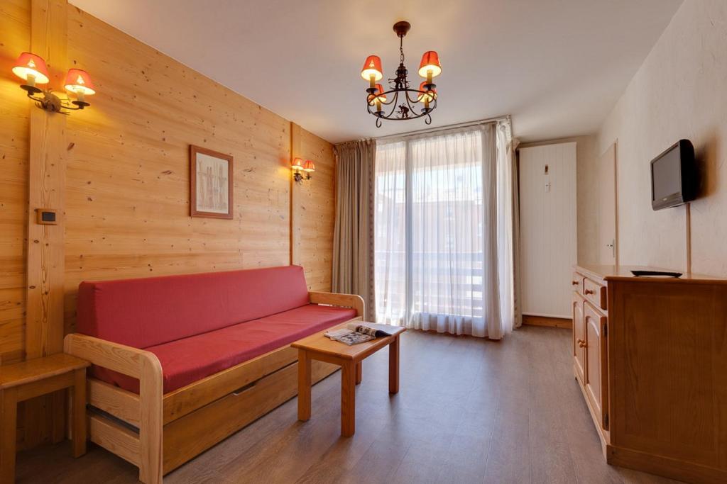 sala de estar con sofá rojo y lámpara de araña en Vacancéole - Résidence Les Bleuets en Les Deux Alpes