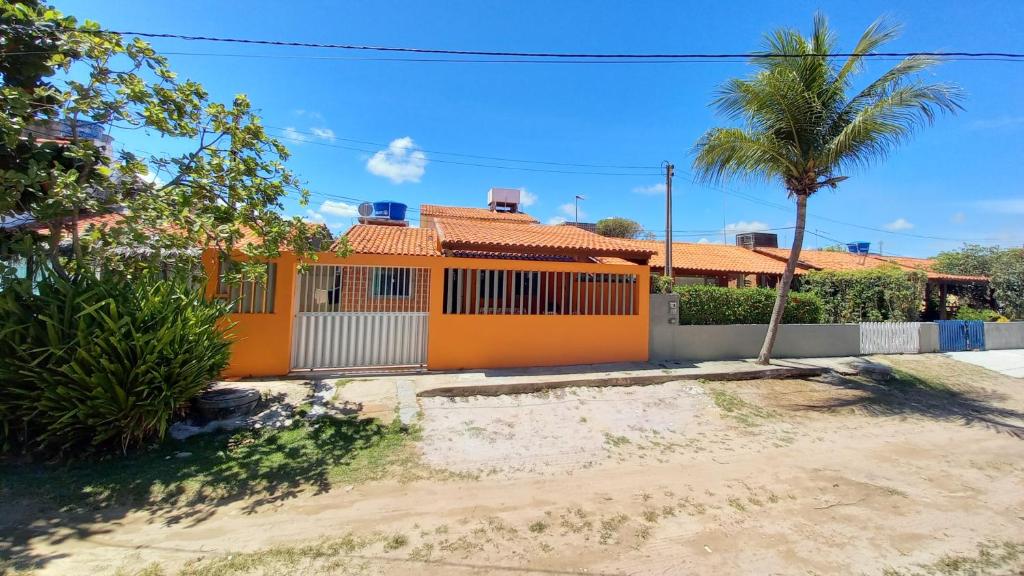 an orange fence in front of a house with a palm tree at Casa de praia in Porto De Galinhas