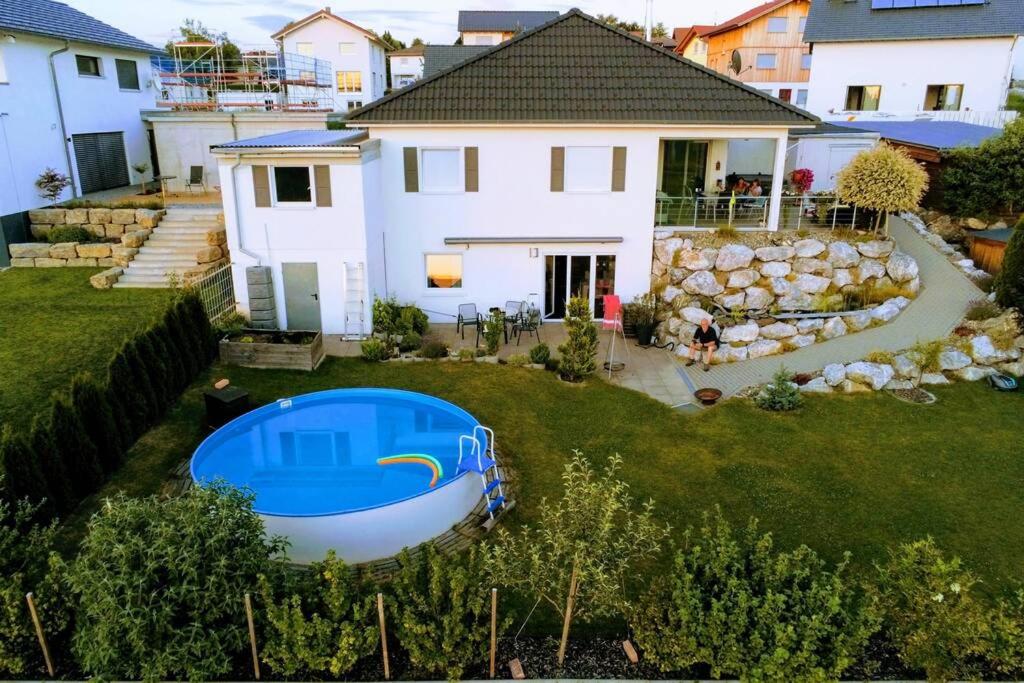 ein weißes Haus mit einem blauen Boot im Hof in der Unterkunft Allgäu gemütliche, moderne Wohnung mit Garten-Pool in Argenbühl