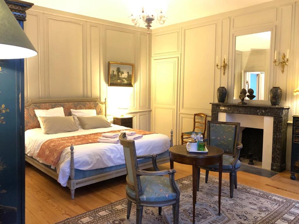 a bedroom with a bed and a table and chairs at Castel Saint-Léonard in Falaise