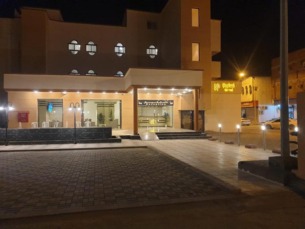 un edificio con luces en un estacionamiento por la noche en الحساني بلازا أضم, en Adham