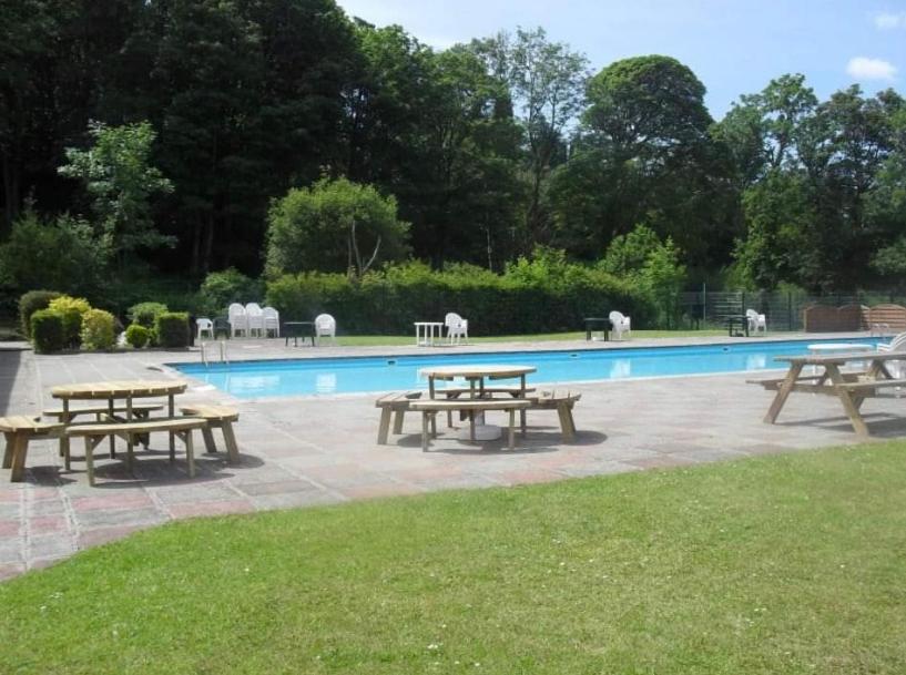 grupa stołów piknikowych przed basenem w obiekcie SNOWDON LODGE Luxury Lodge Glan Gwna Holiday Park Caeathro Caernarfon Near Snowdonia w mieście Caernarfon