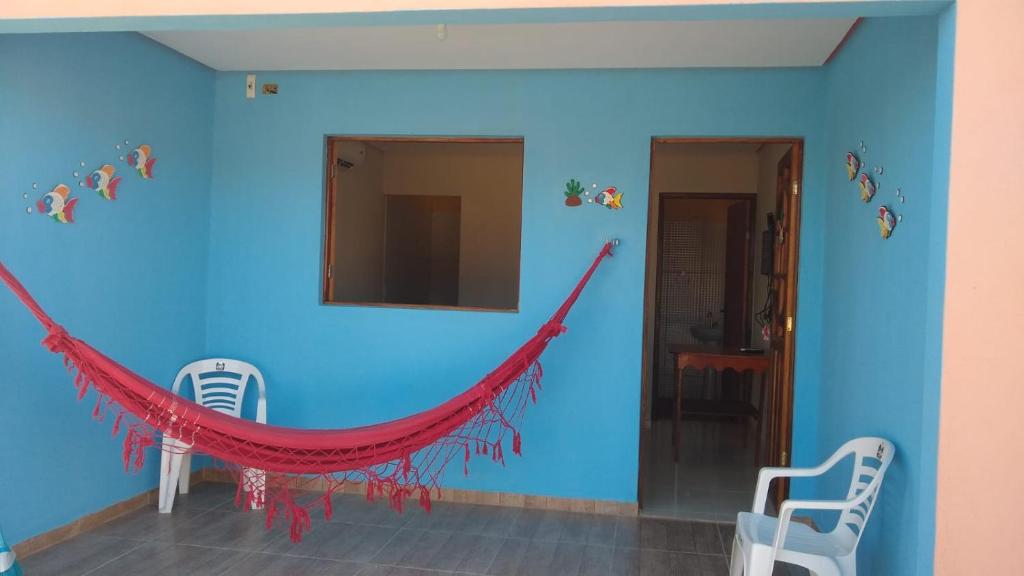 a blue room with a red hammock on the wall at casa morada da praia in Xeréu