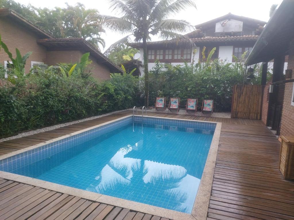 uma piscina num quintal com um deque de madeira em Casa na praia de Itamambuca na cidade de Ubatuba em Ubatuba