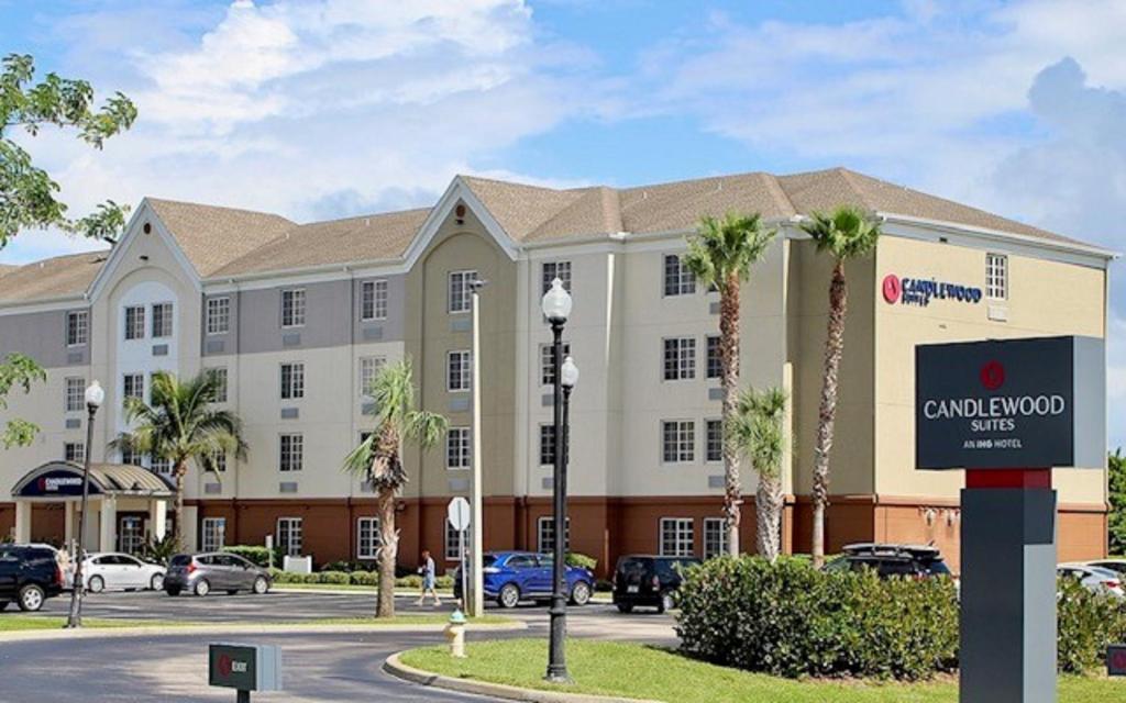 a large building with palm trees in a parking lot at Candlewood Suites Melbourne/Viera, an IHG Hotel in Melbourne