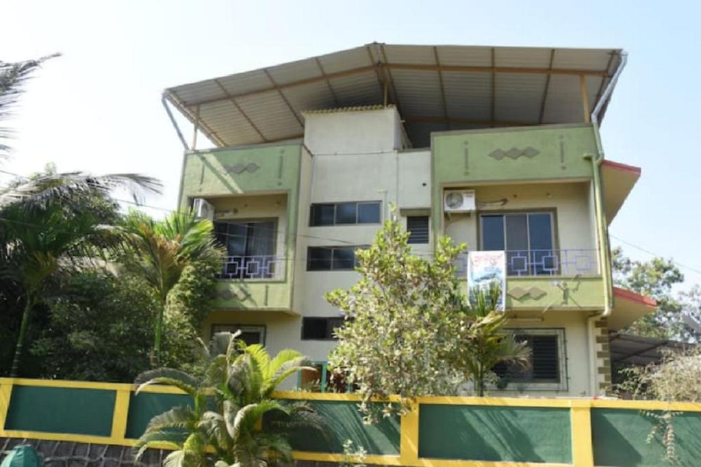 阿利鲍格Gulmohar Cottages - Home Stay in Alibag的前面有大量树木的建筑