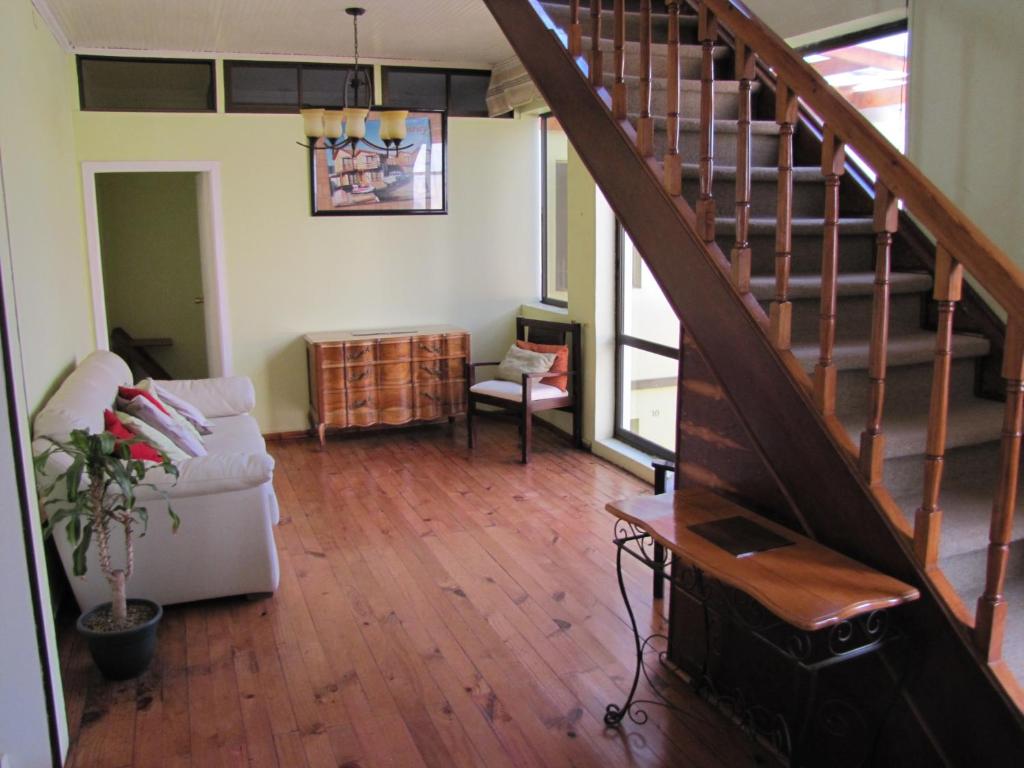 a living room with a staircase and a couch at Hostal Antumulen in Pichilemu