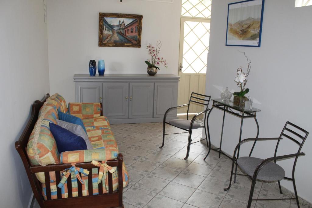 uma sala de estar com um sofá, uma mesa e cadeiras em Vila Marias em Ouro Preto