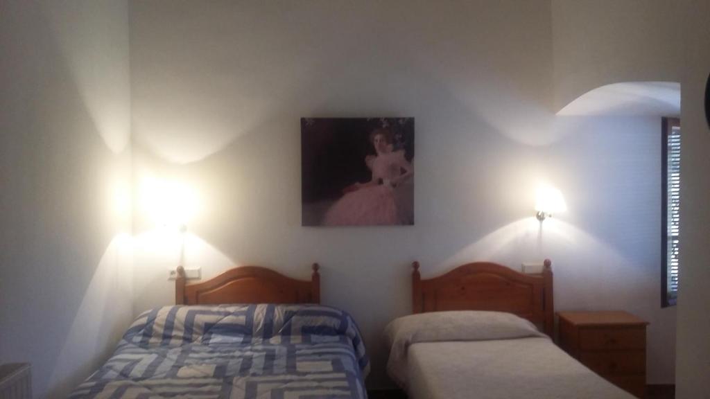 a bedroom with two beds and two lights on the wall at Habitacion de la marquesa in Alcoleja