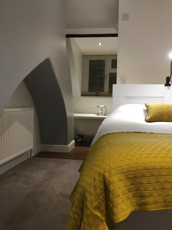 um quarto com uma cama com um cobertor amarelo e um lavatório em Countryside townhouse 