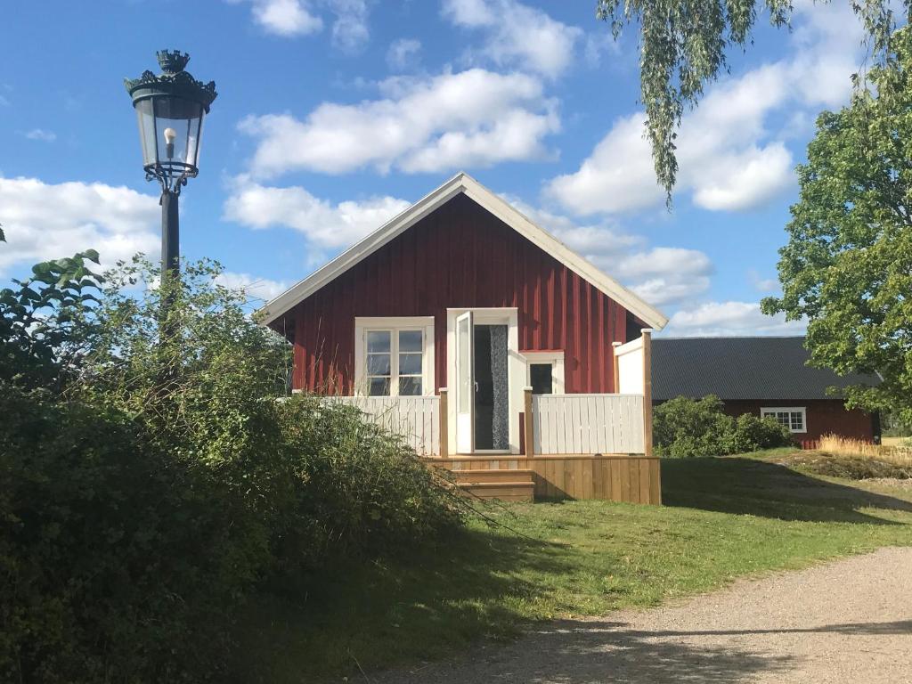 een rode schuur met een straatlicht ervoor bij Nice holiday house at horse farm with lake and sauna in Hölö