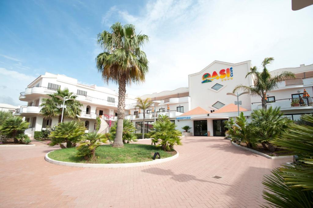 a palm tree in front of a white building at Oasiclub Hotel in Vieste