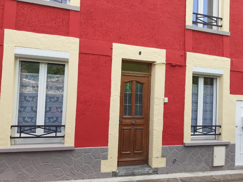 een rood en geel gebouw met een houten deur bij La maison du bonheur in Fumay