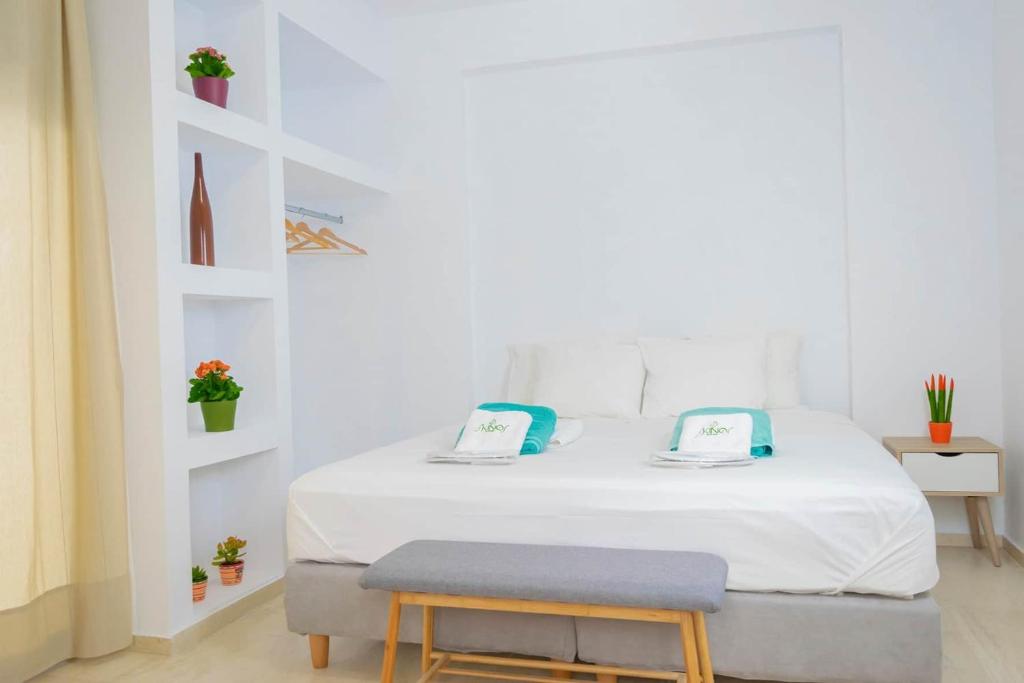 a white bedroom with a large white bed with a bench at Skinosummer in Paralia Agias Foteinis