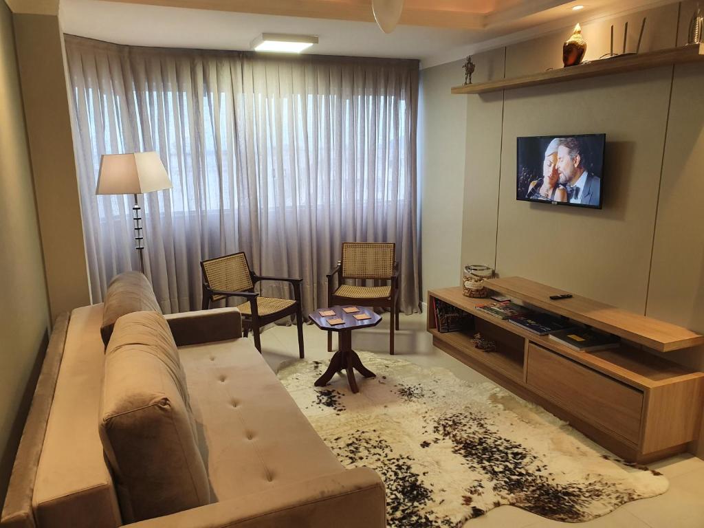 a living room with a couch and a flat screen tv at Quadra do mar. Lindo apto em Balneário Camboriú. in Balneário Camboriú