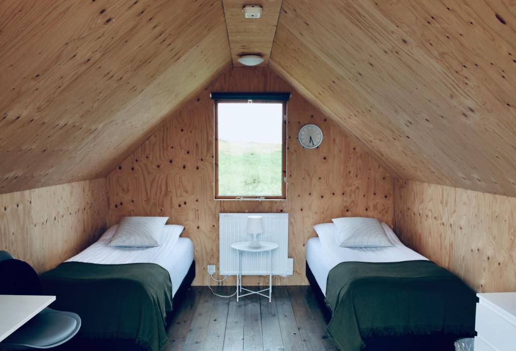 two beds in a wooden room with a window at iStay Cottages in Sandger&eth;i