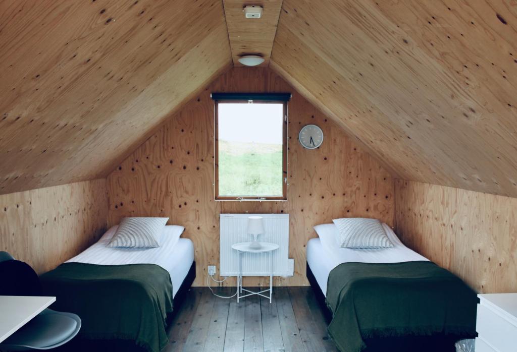 two beds in a wooden room with a window at iStay Cottages in Sandgerði