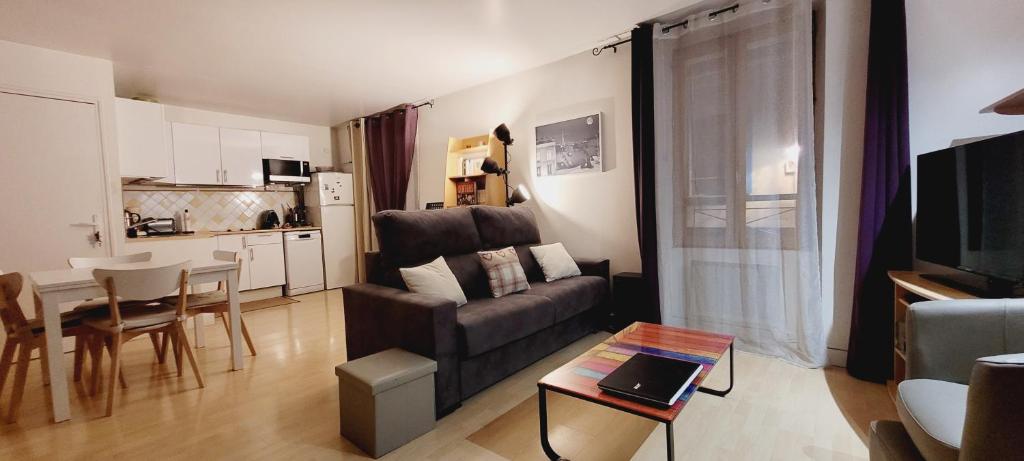Duplex centre Ville في نانتير: غرفة معيشة مع أريكة وطاولة ومطبخ